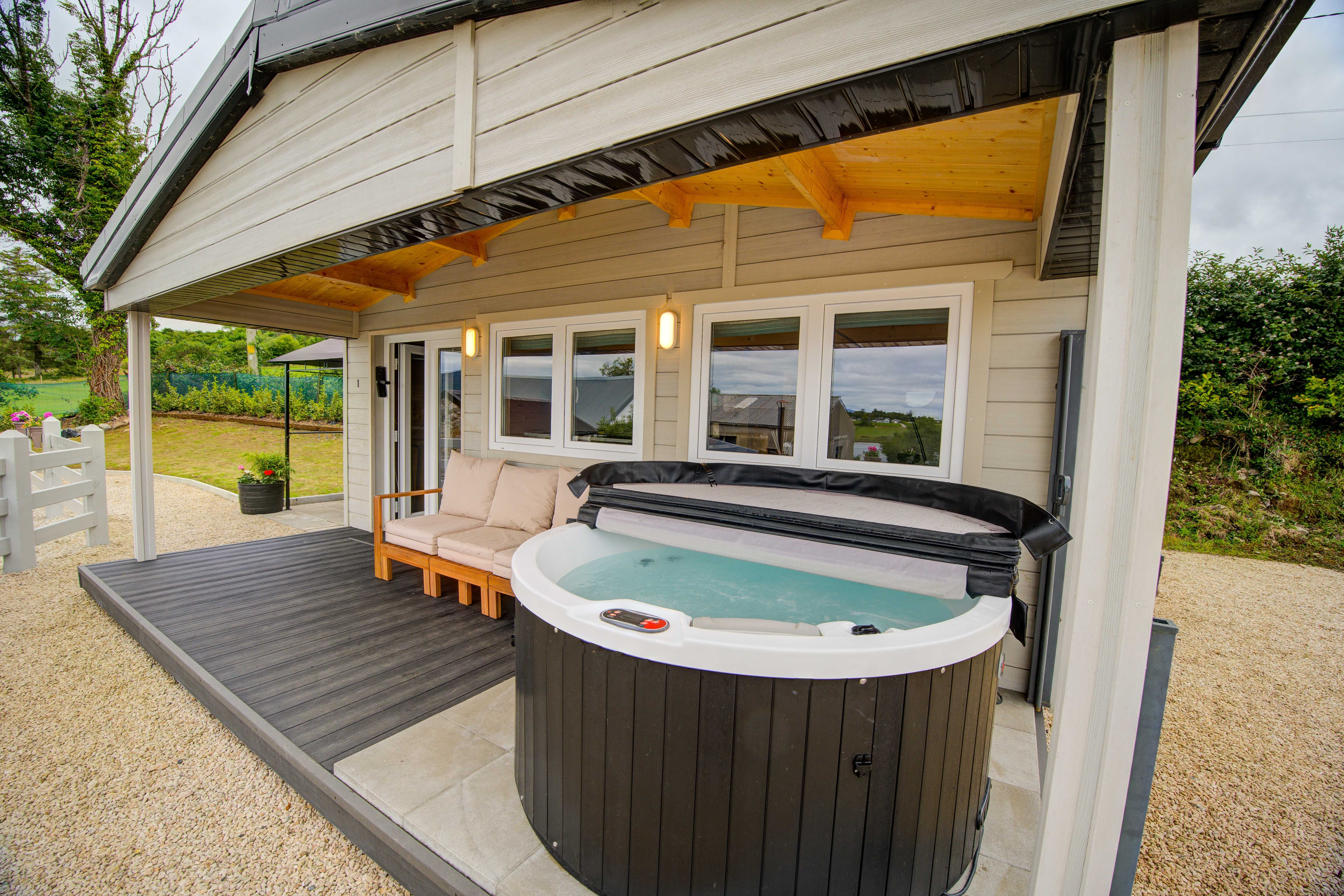 Log Cabin One's covered porch with the uncovered hot tub and a teak sofa