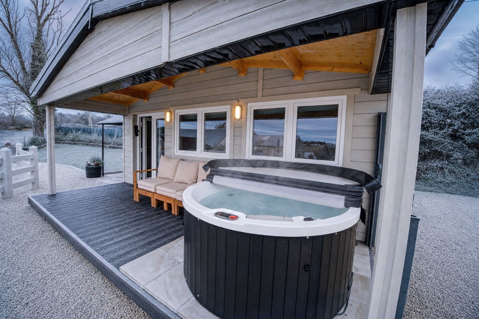 The covered porch and steaming hot tub at Rae’s Cabin on a frosty winter evening