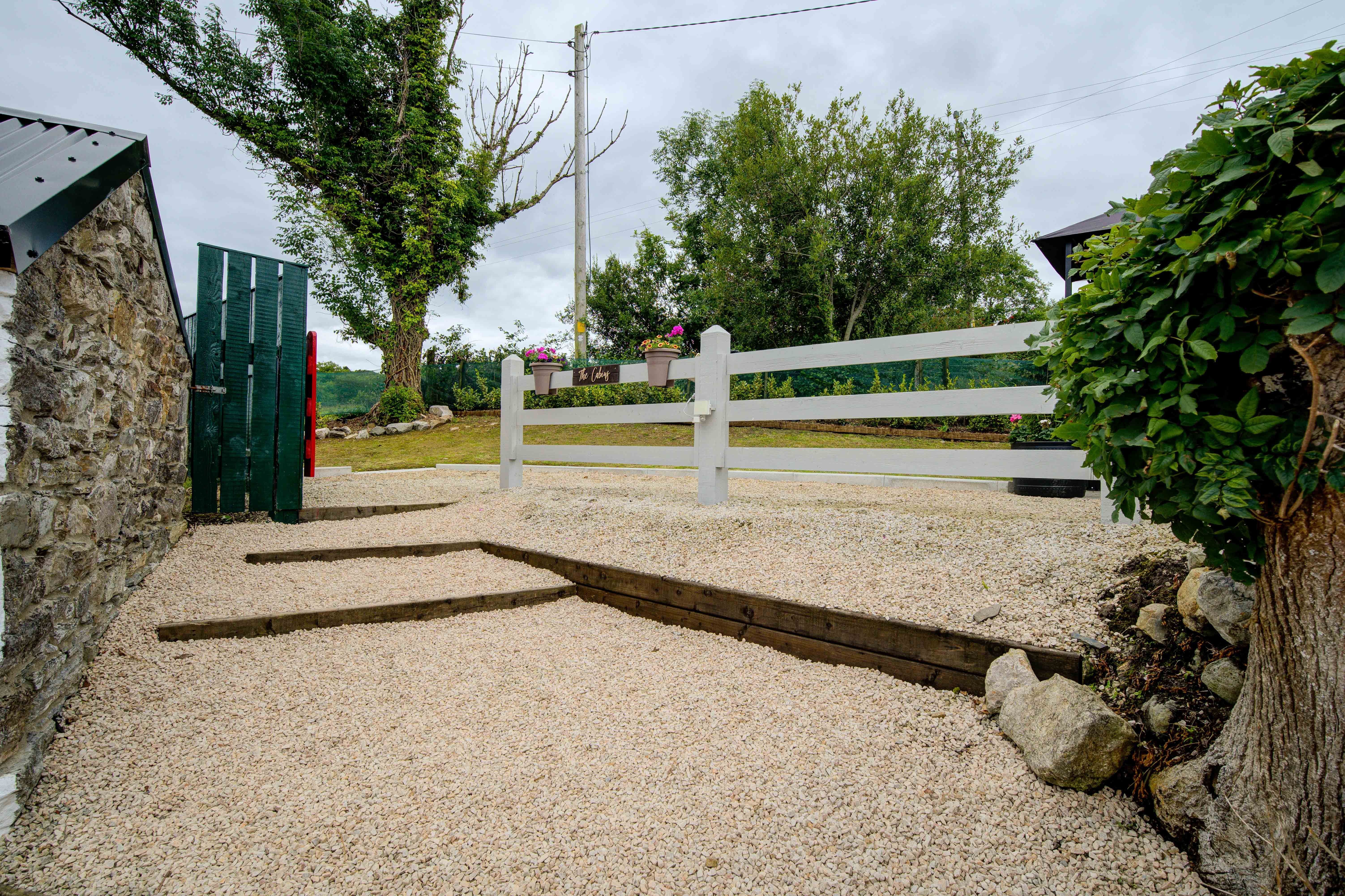 Gravel steps rising through the cabin yard to the green gate on an overcast day