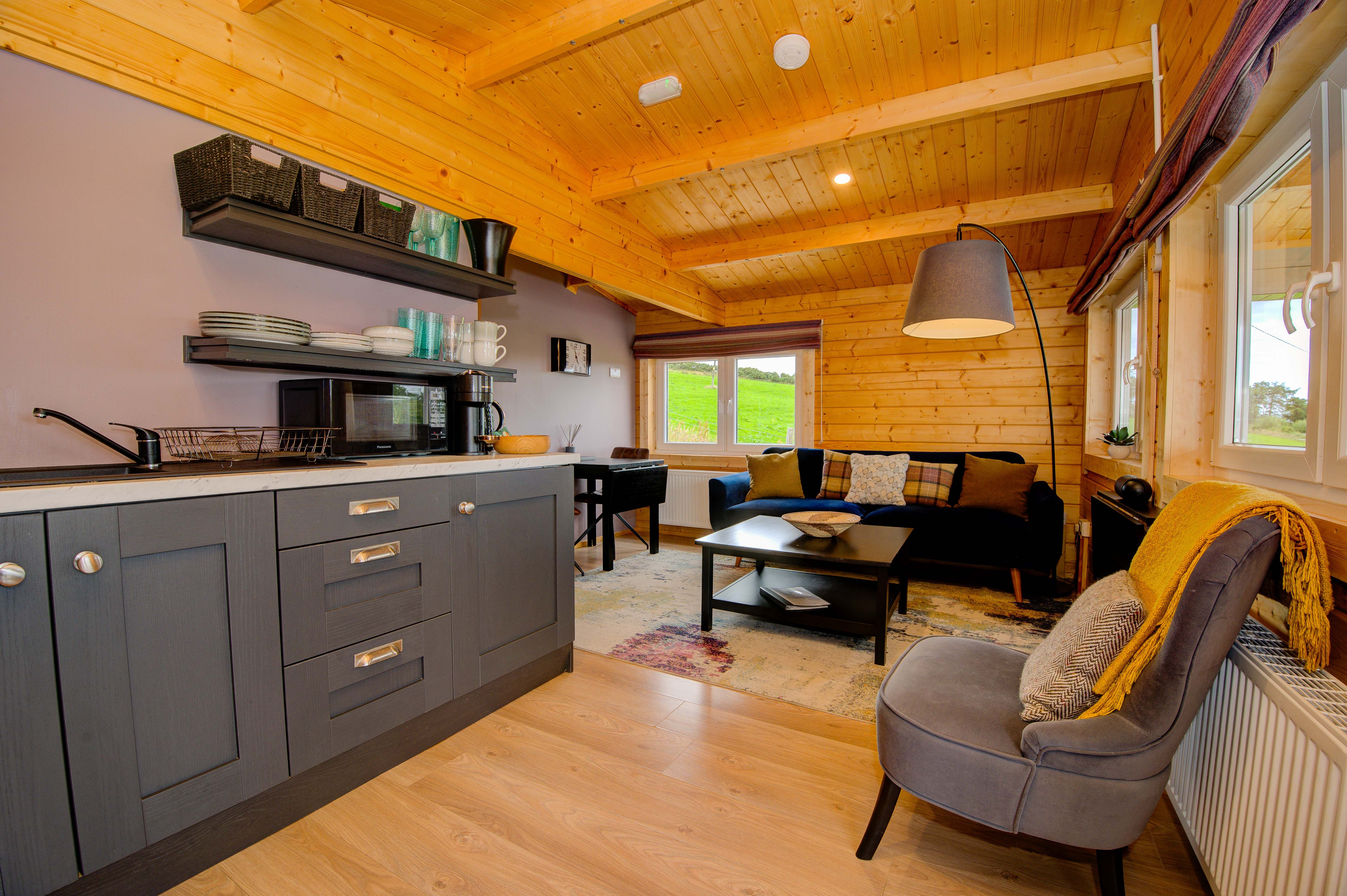 Cabin Two's open-plan living and kitchen, with the heather-toned feature wall and floating shelves