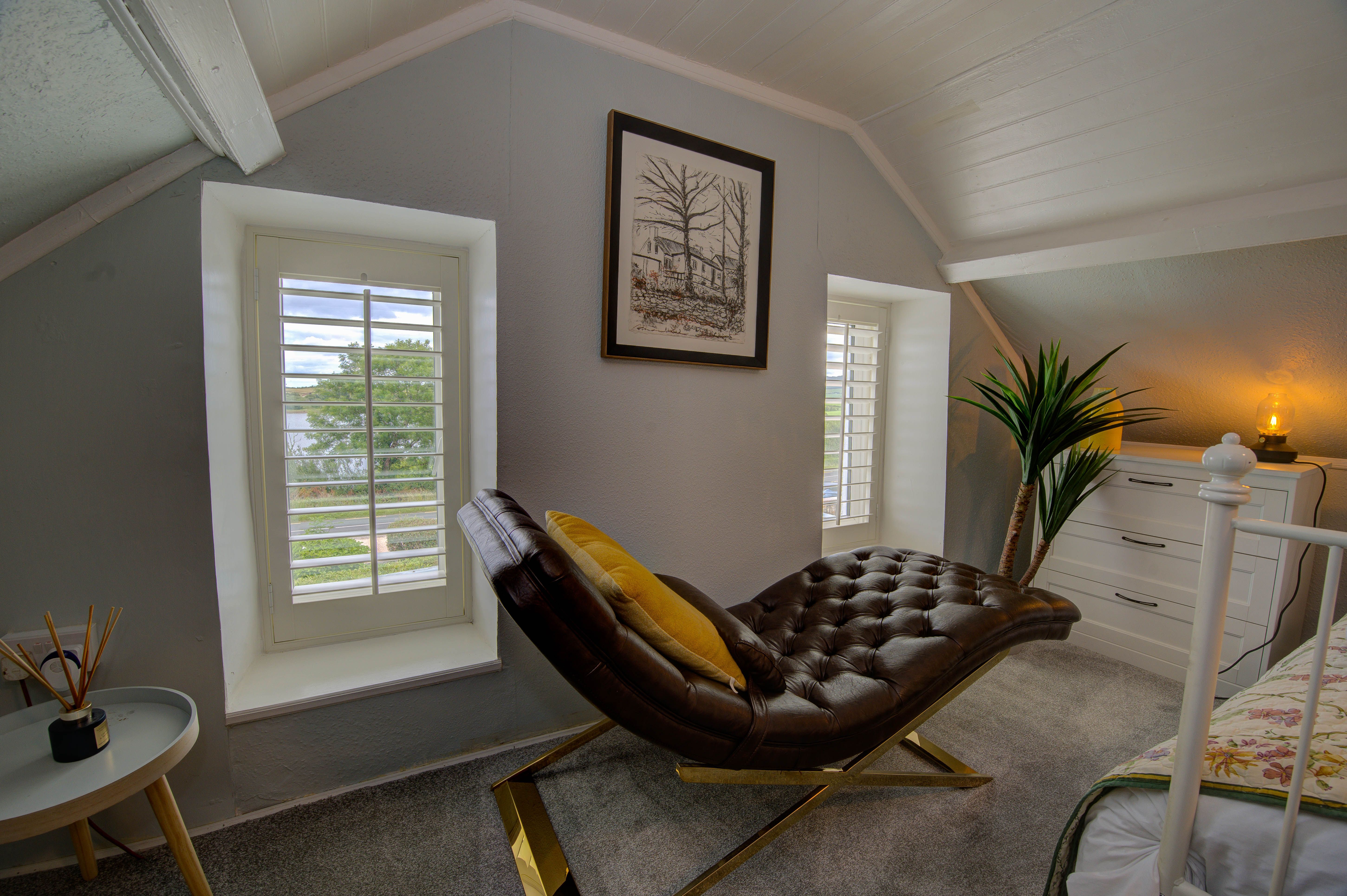 The brown leather chaise in the attic master bedroom, plantation shutters behind.