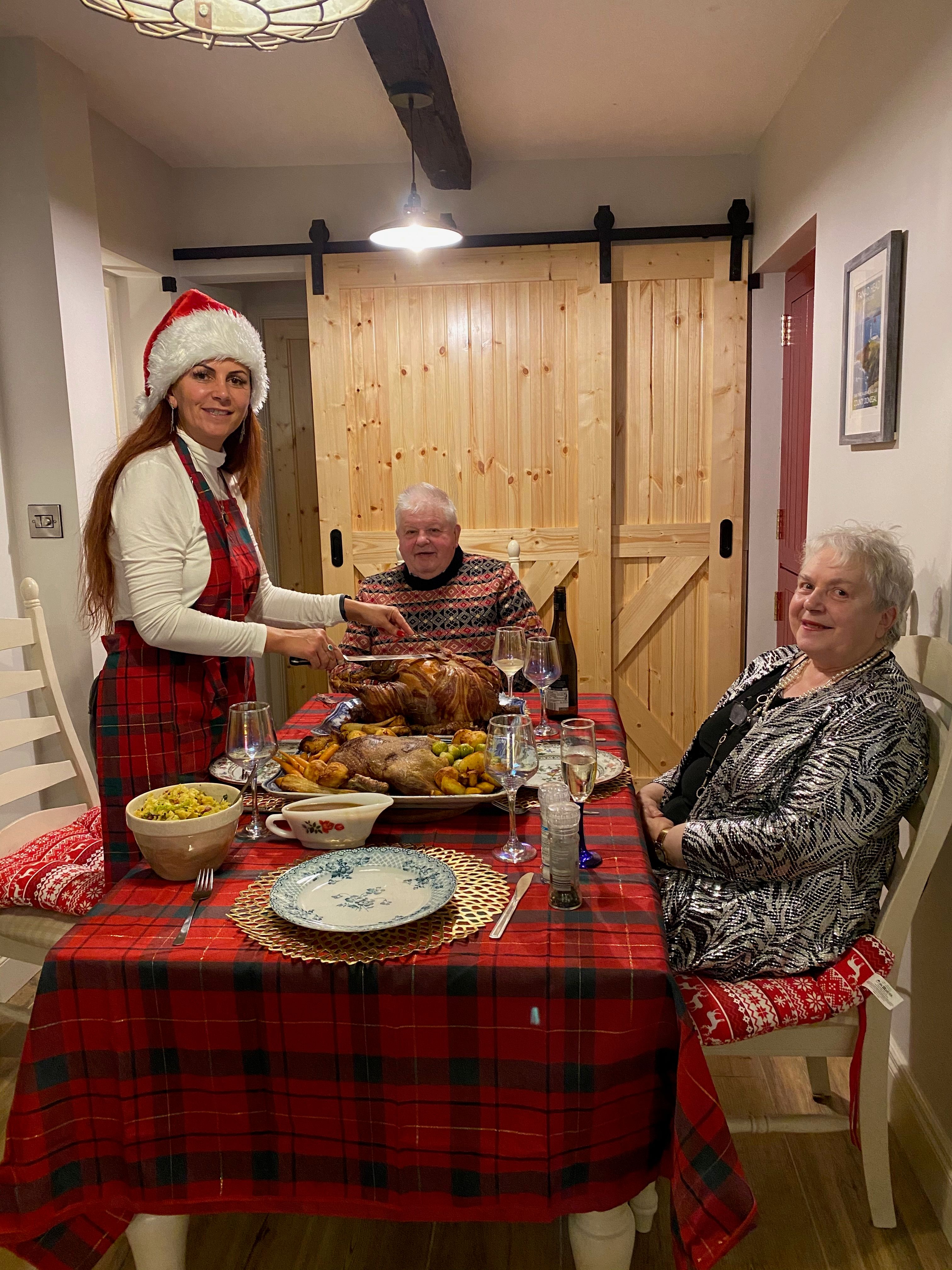 Christmas dinner at the cottage table, the meal laid out and the new pine barn doors behind — the finished room in use.