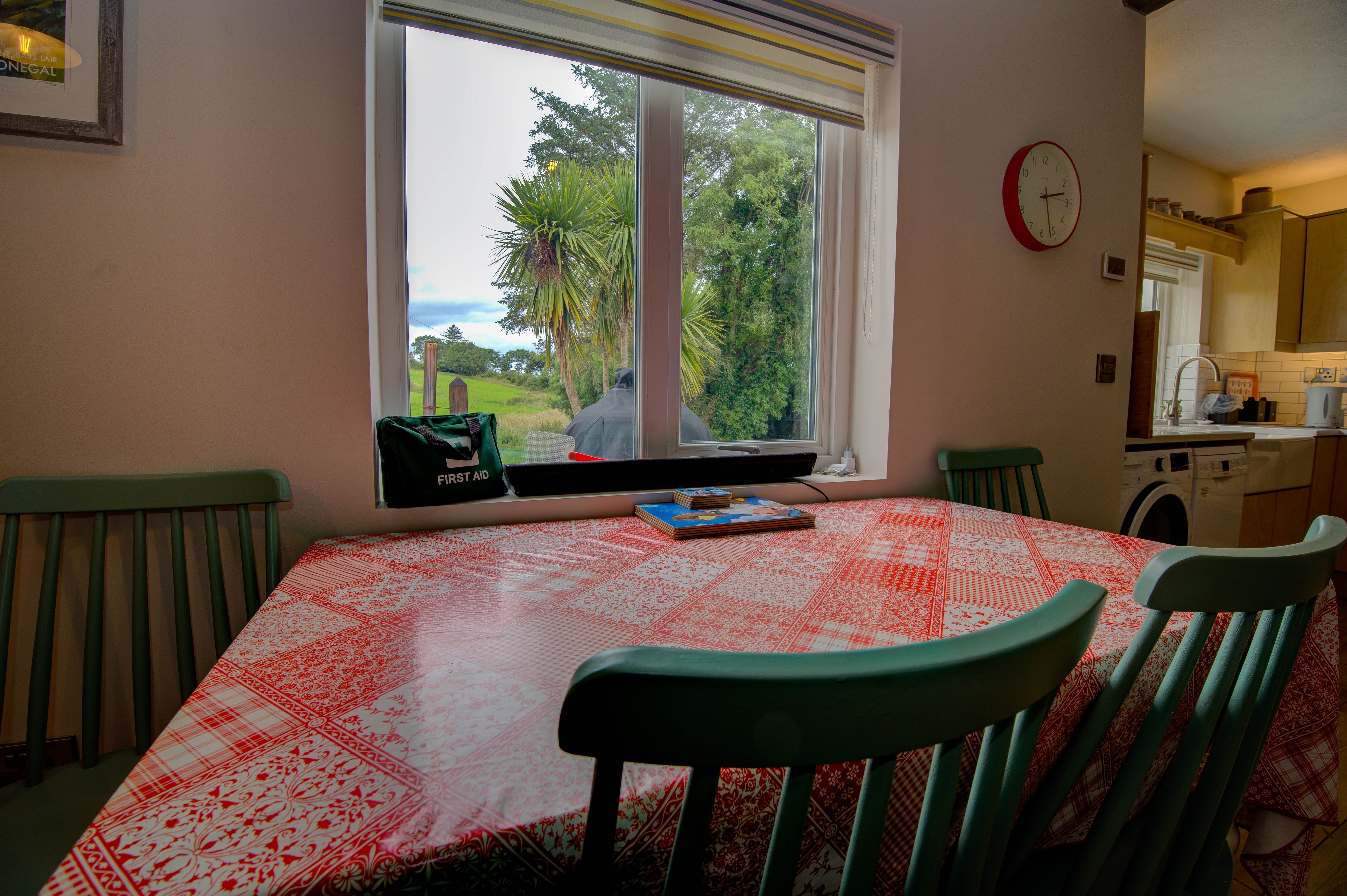 The cottage dining table under the window, palms in the garden beyond