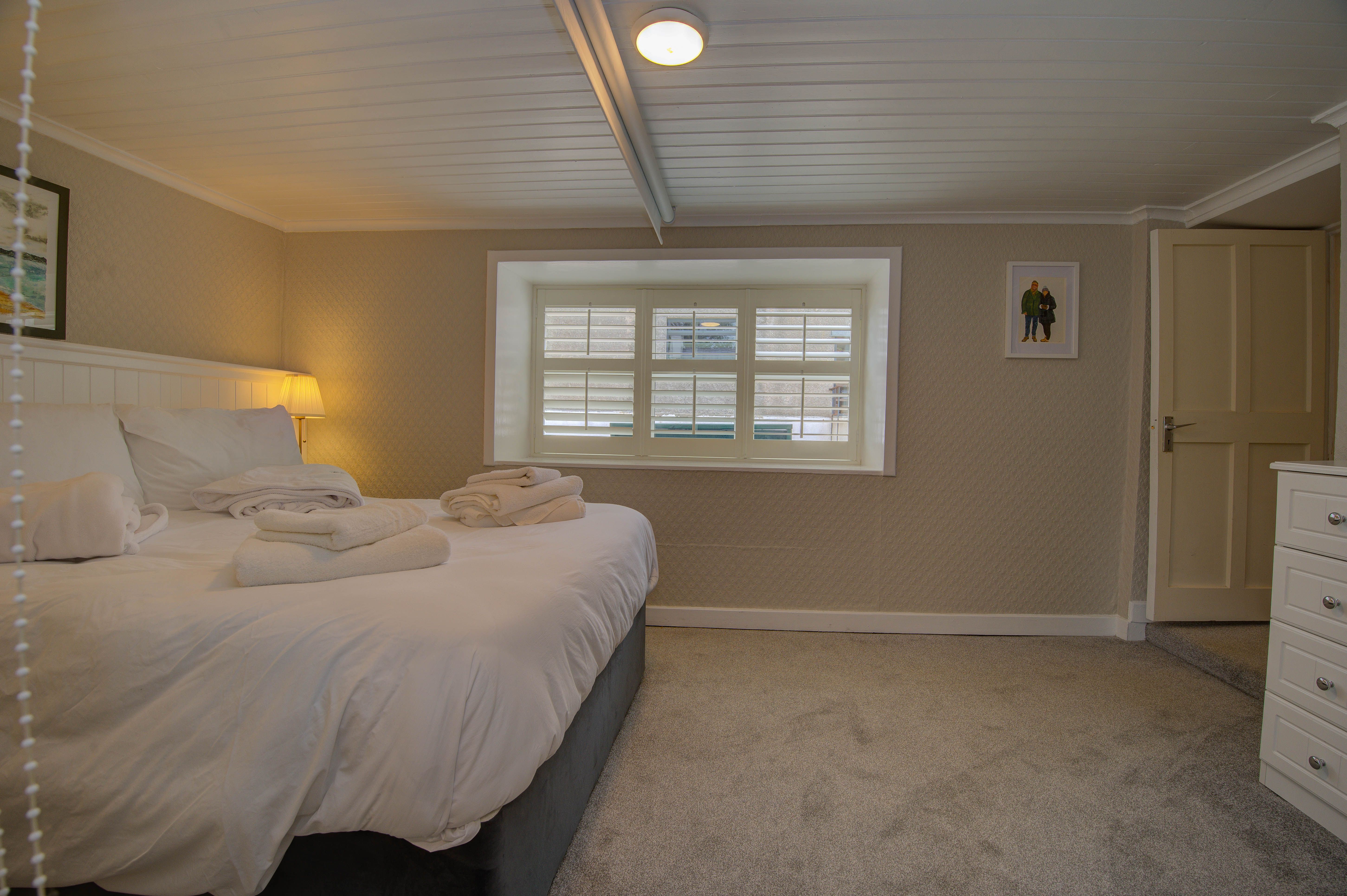 The downstairs double bedroom, white linen and shuttered window