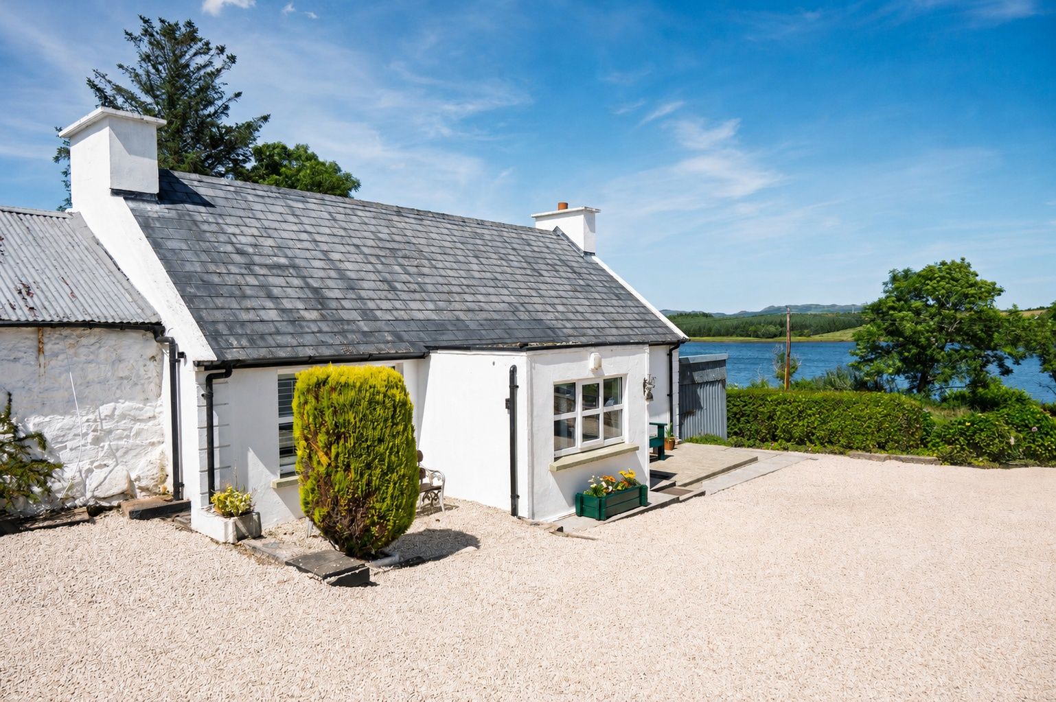 The cottage exterior — whitewashed walls and slate roof in the sun