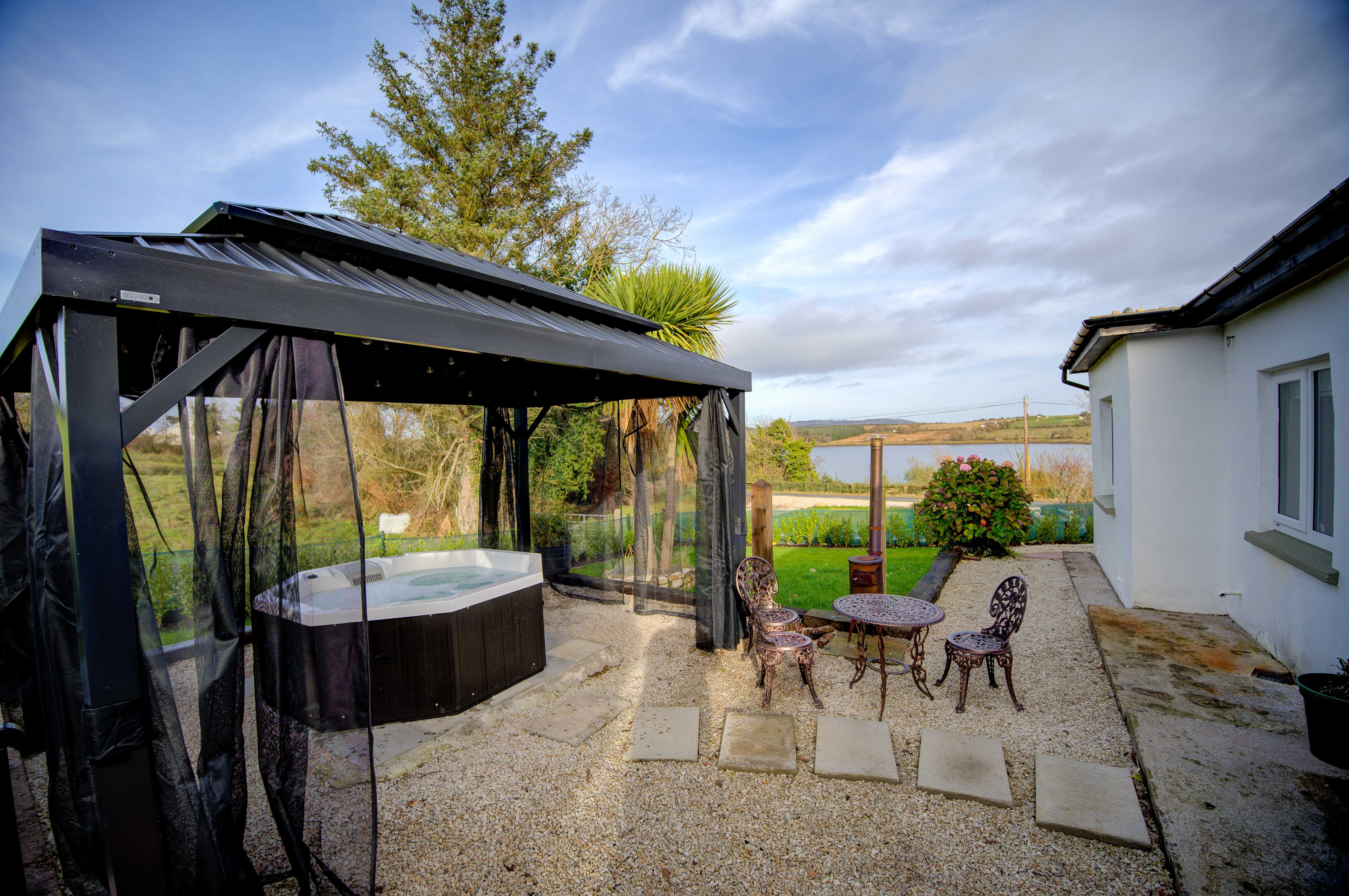 The cottage gazebo and hot tub with the BBQ to one side