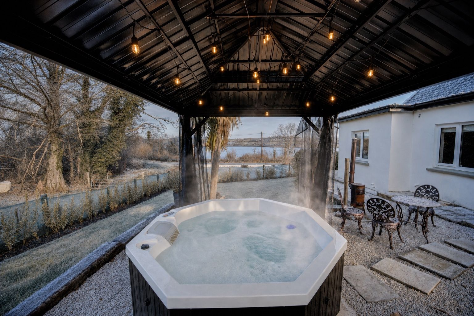 The cottage hot tub steaming under the gazebo’s lit string lights, frost on the winter garden and Mulroy Bay beyond