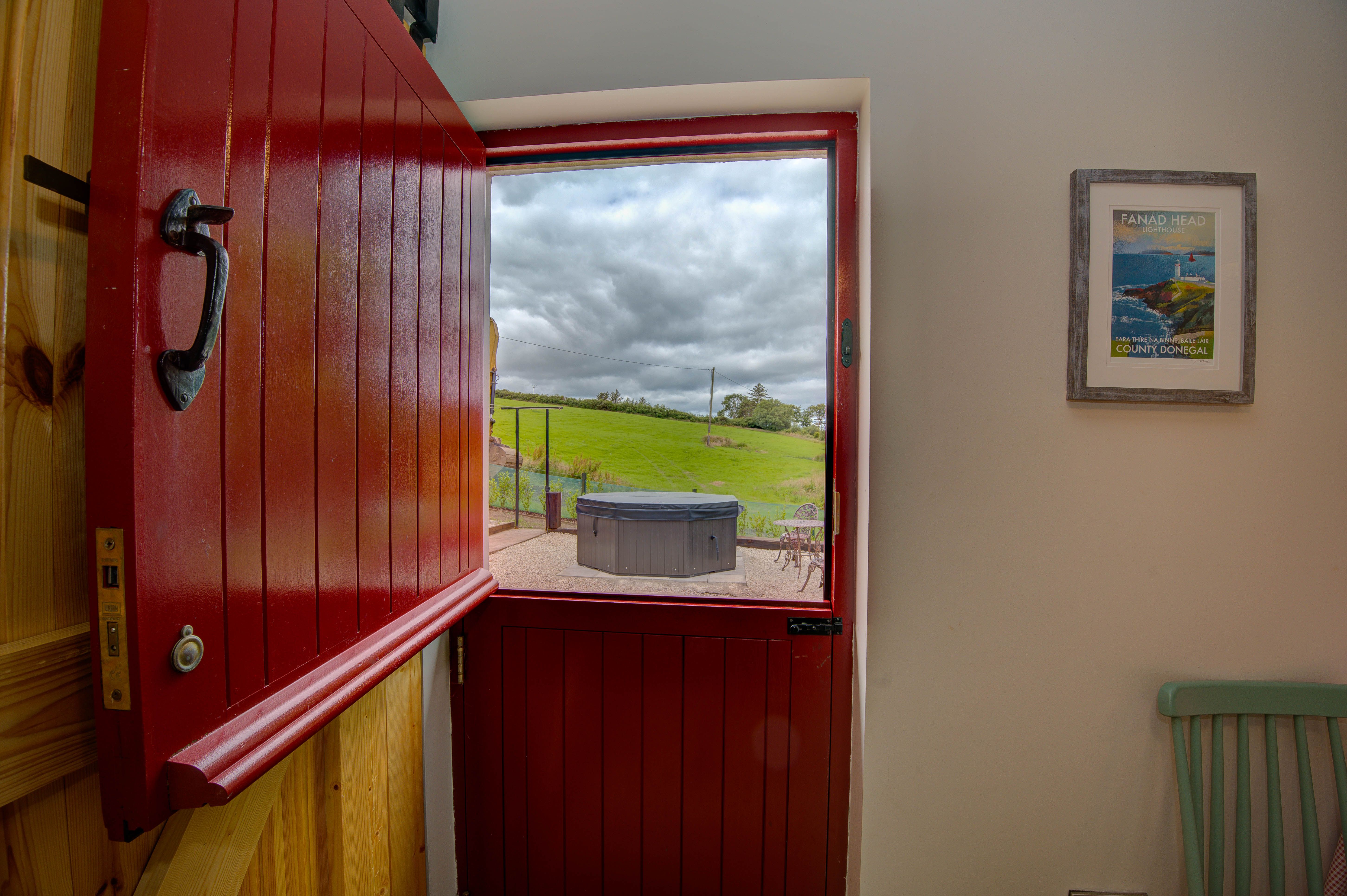 The red half door open from inside the cottage, the private hot tub and field beyond