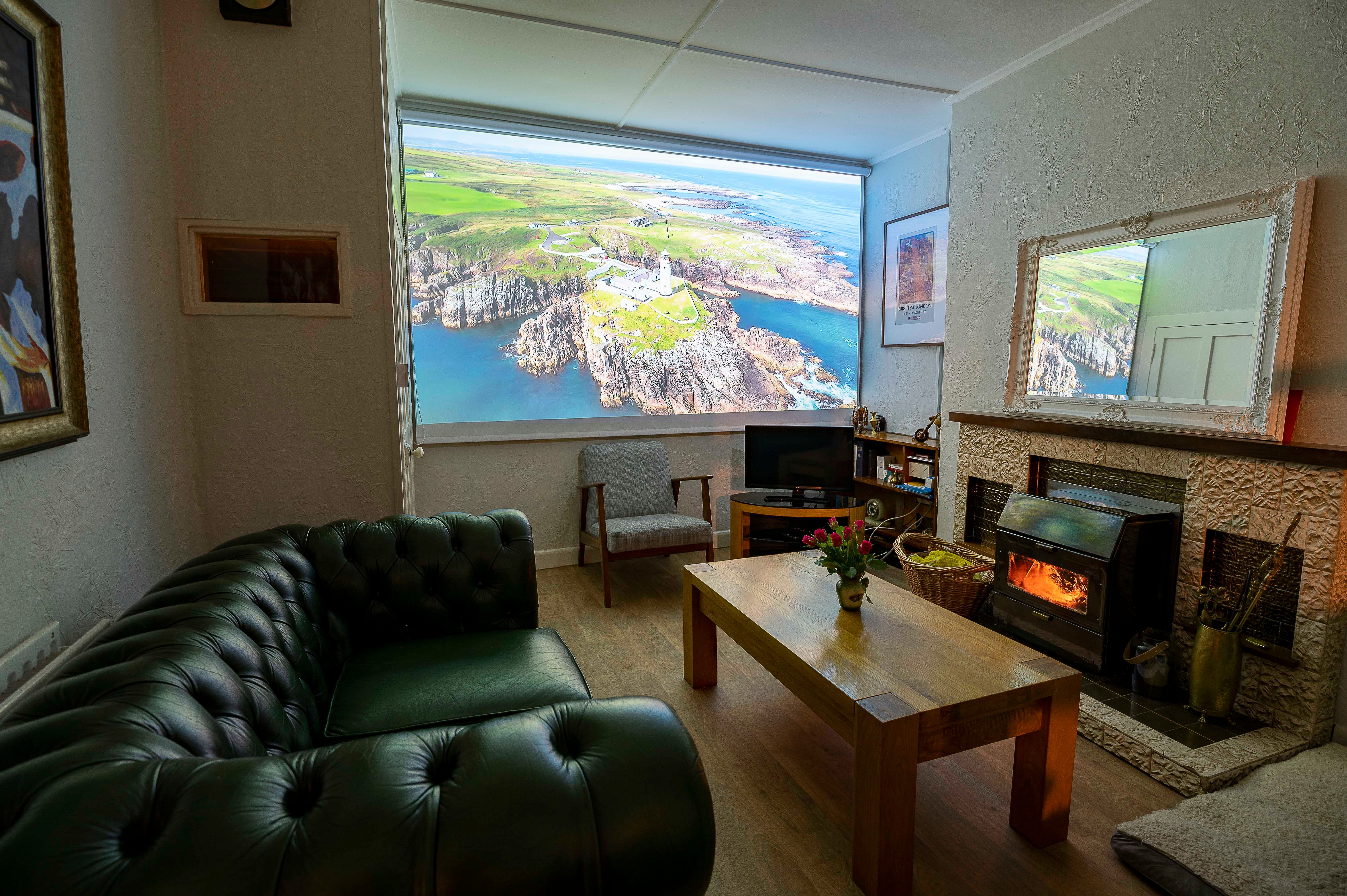 The cottage sitting room set for a film, the projector screen down showing an aerial of Fanad Head.