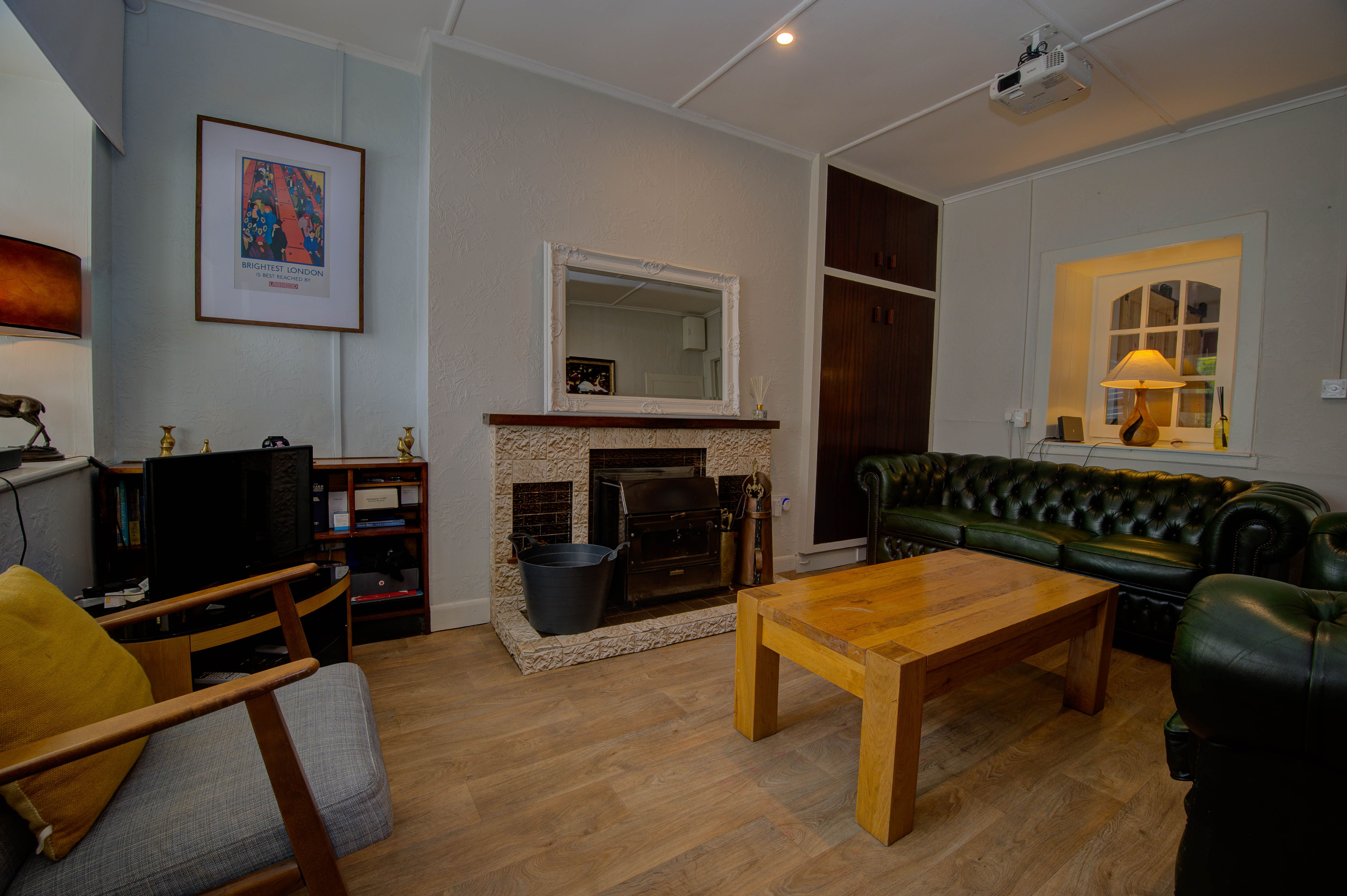 The cottage wood-burner in the white-tiled fireplace surround, logs beside it