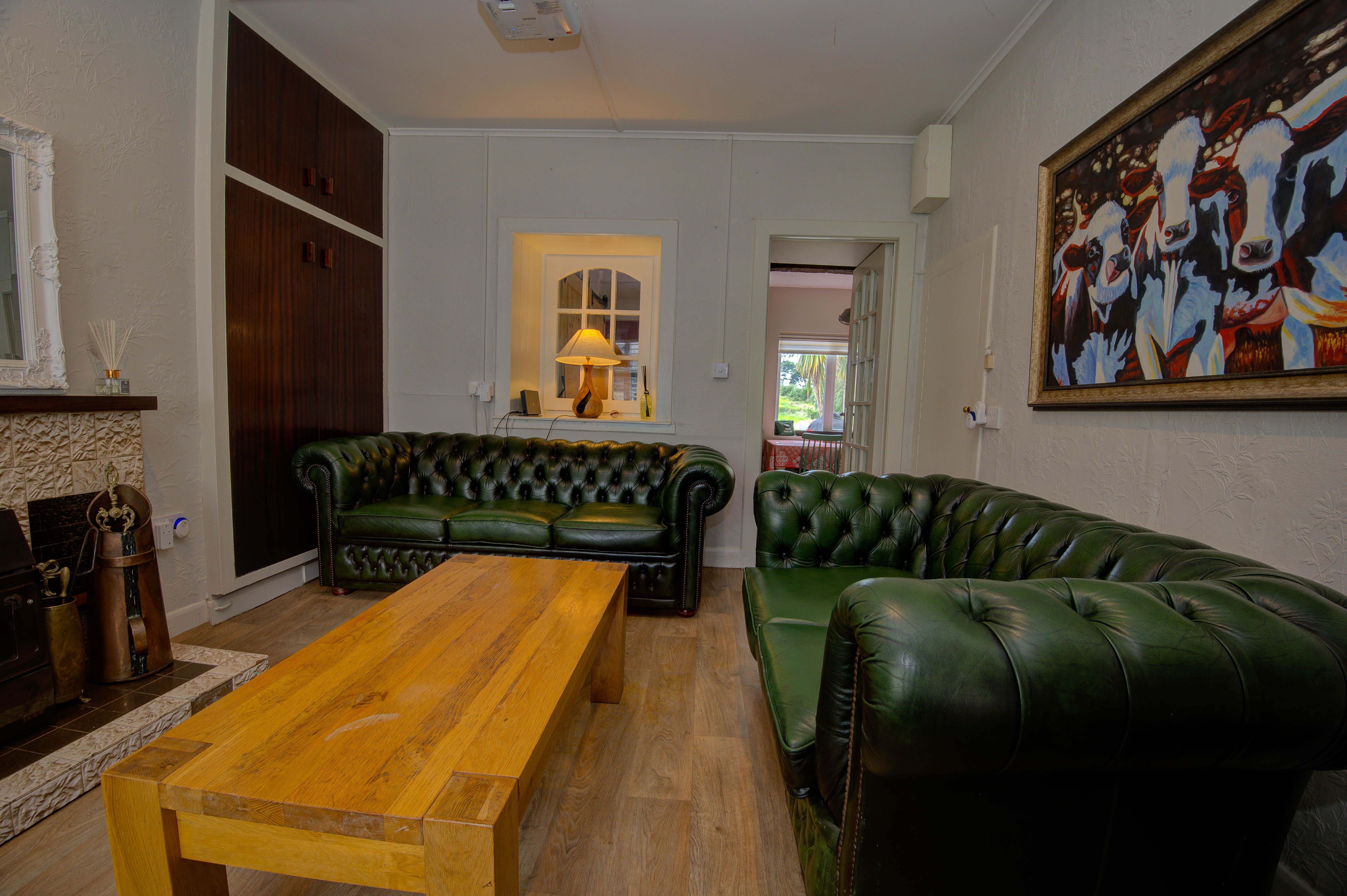 The cottage sitting room — two green Chesterfield sofas and the cast-iron stove