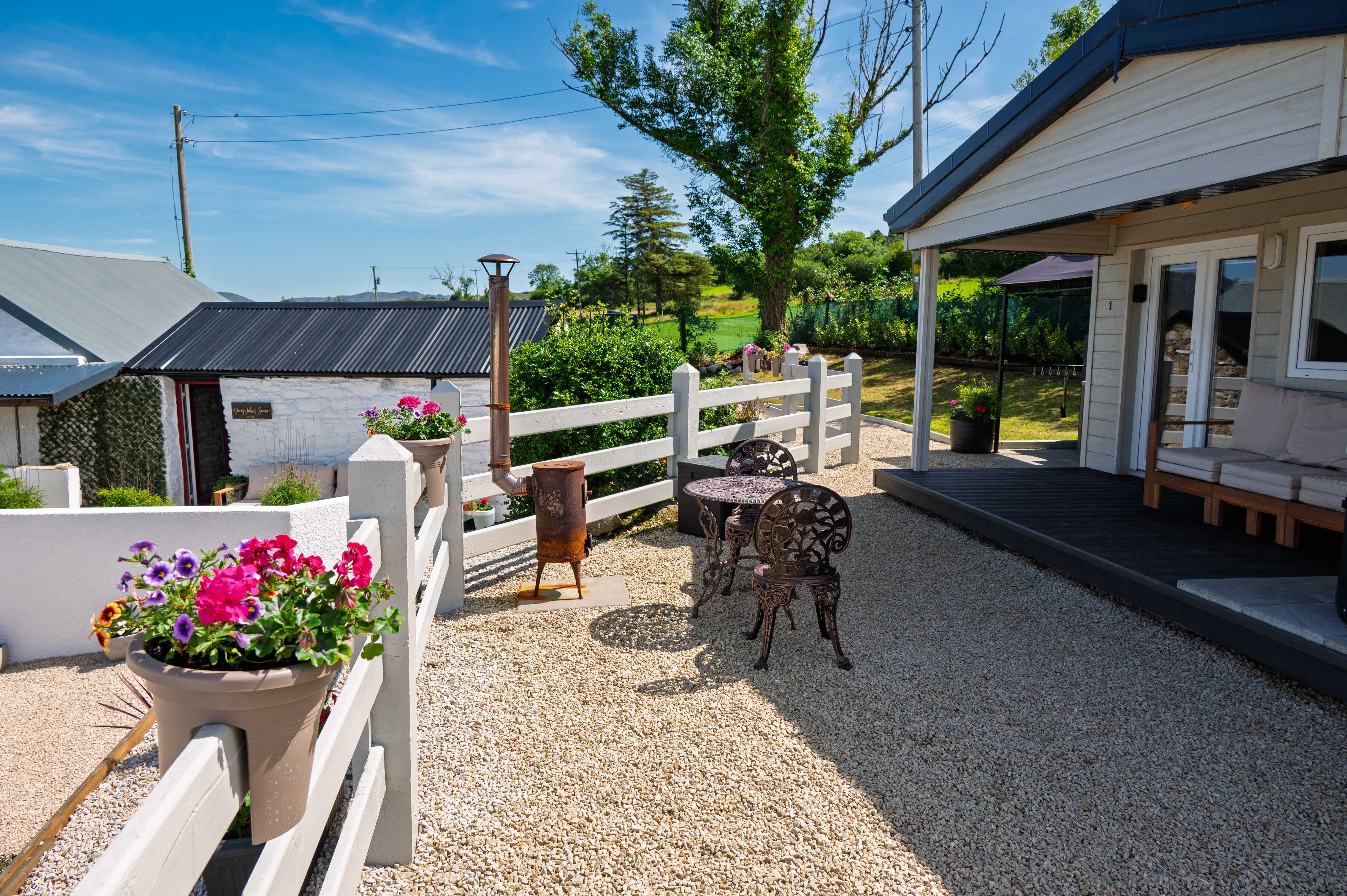 The quartz-paved courtyard between buildings — the bistro set, the sauna door, the cabin beyond