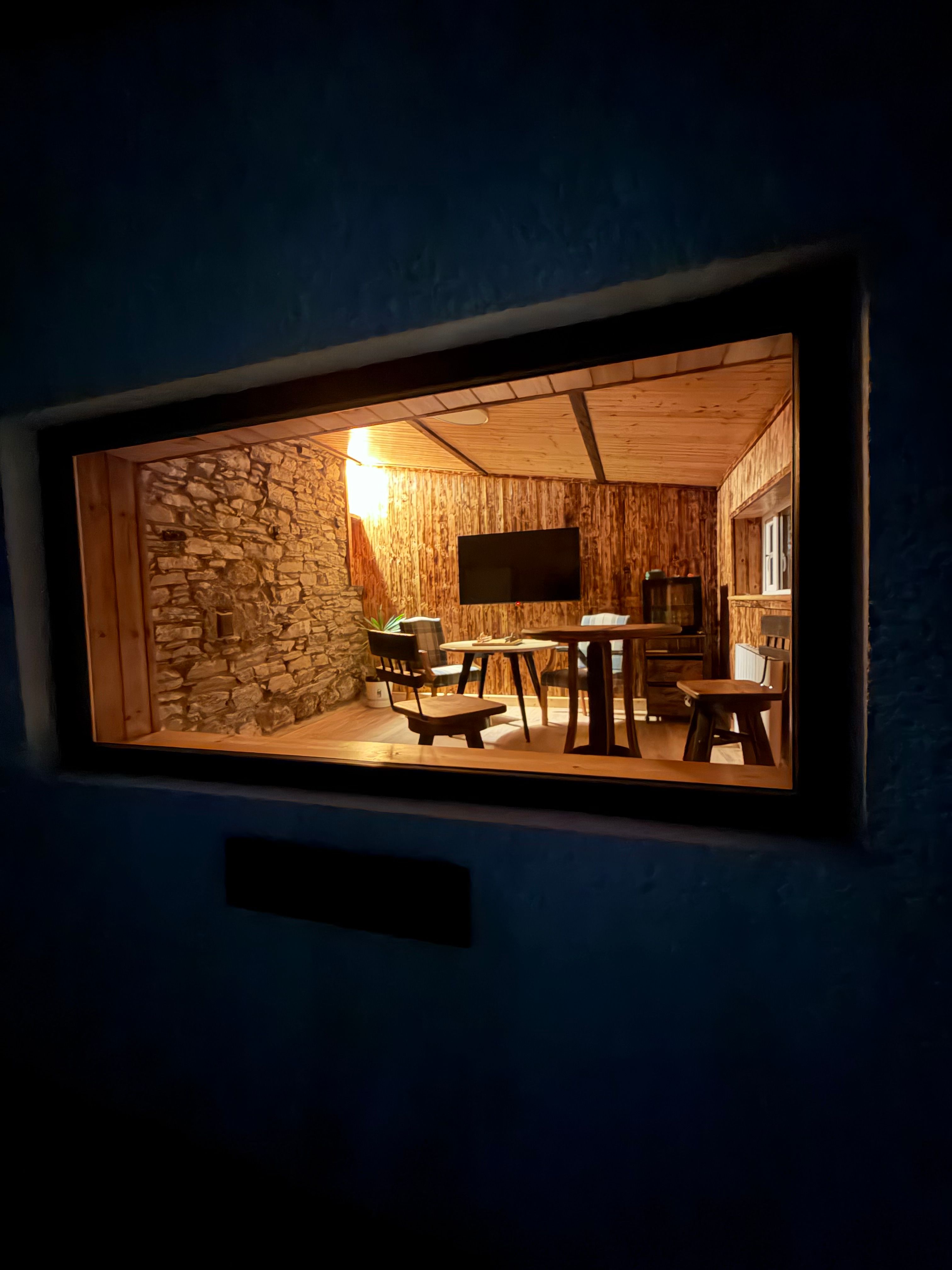 The warmly-lit games room seen through the stone aperture of the dark exterior anteroom
