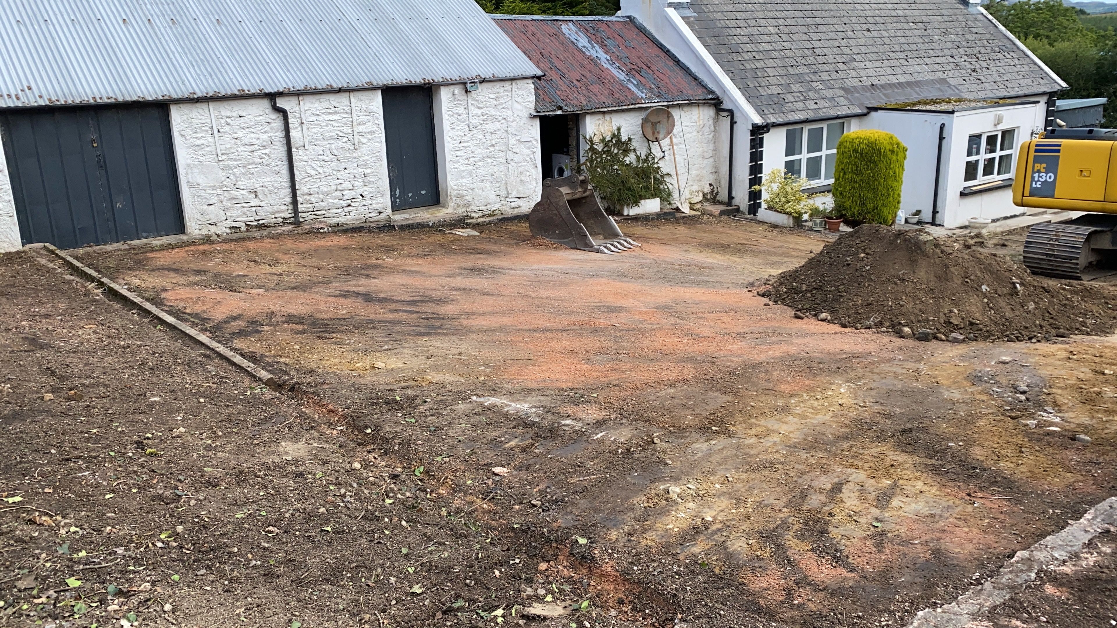 The yard dug back to bare ground during the works, the outbuildings and cottage around it, ready for the new stone.