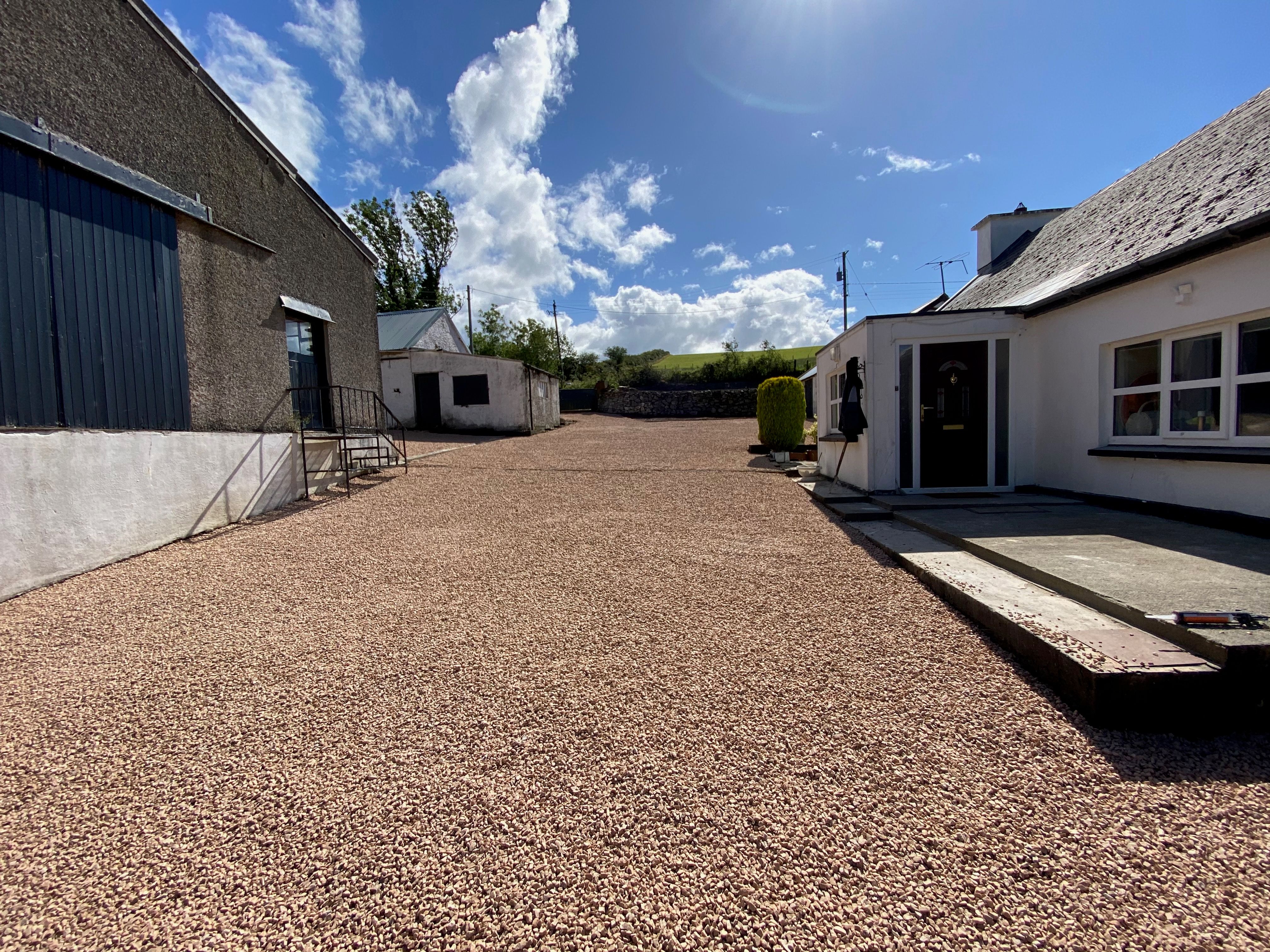 The new pea-gravel laid and raked across the courtyard in sunshine, the cottage with its red door to one side.