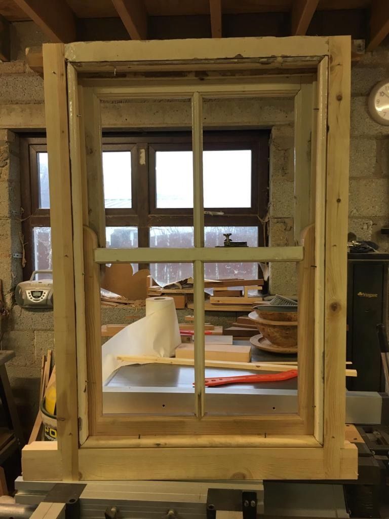 The little timber sash window being restored on the workshop bench, clamped up in fresh softwood.