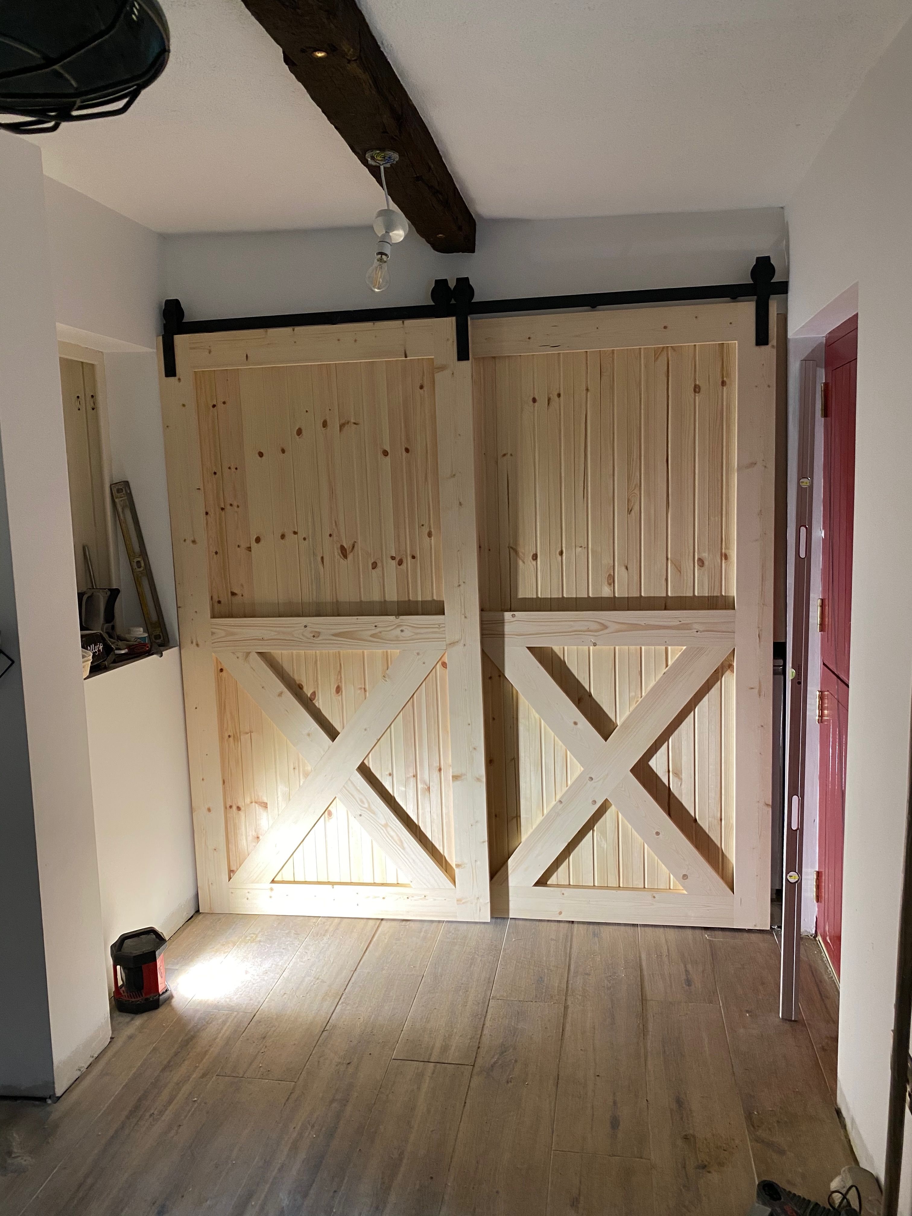 The sliding barn door in situ in the cottage, an X-braced pine door on a black top-track.