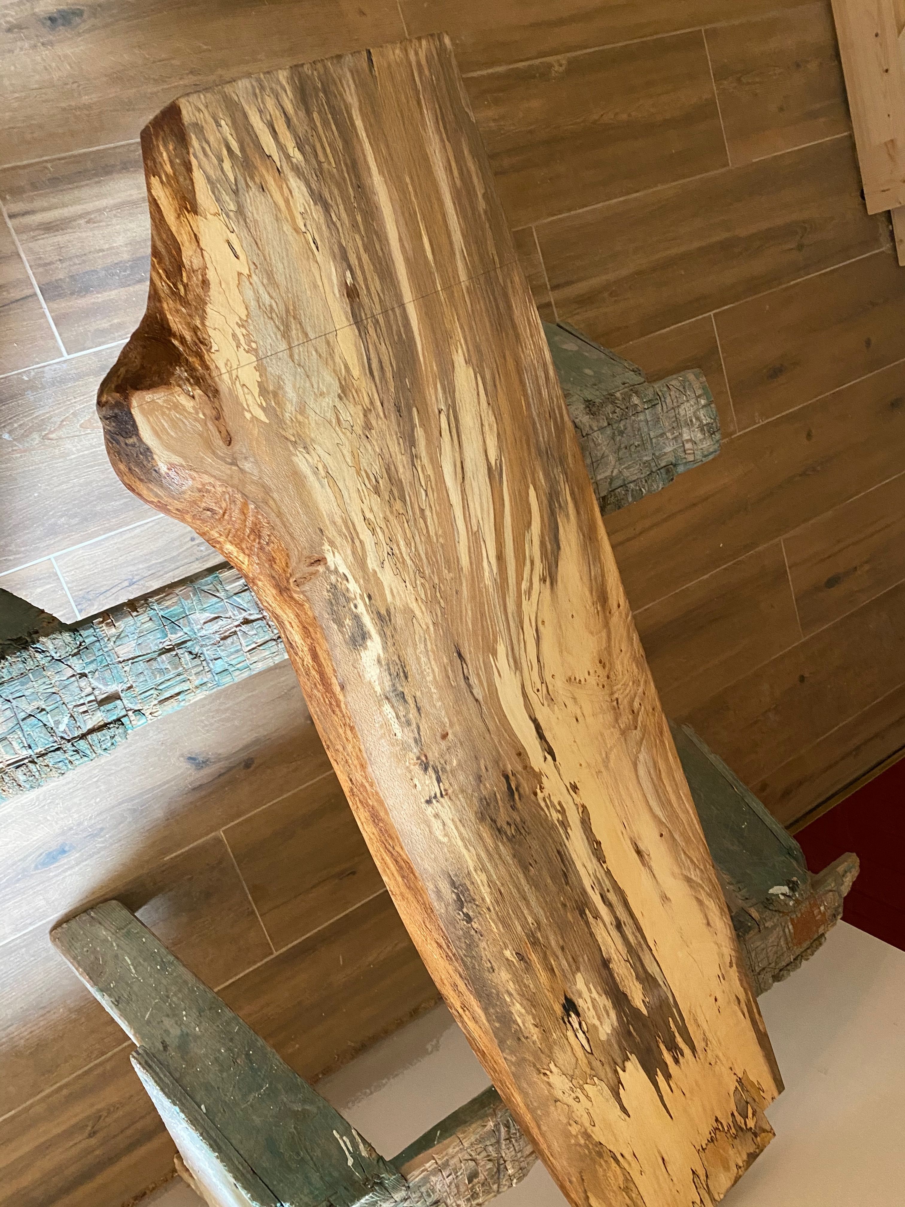 A waney-edge timber slab on trestles, its natural edge intact — the piece of the fallen Mulroy estate tree worked into a window ledge.