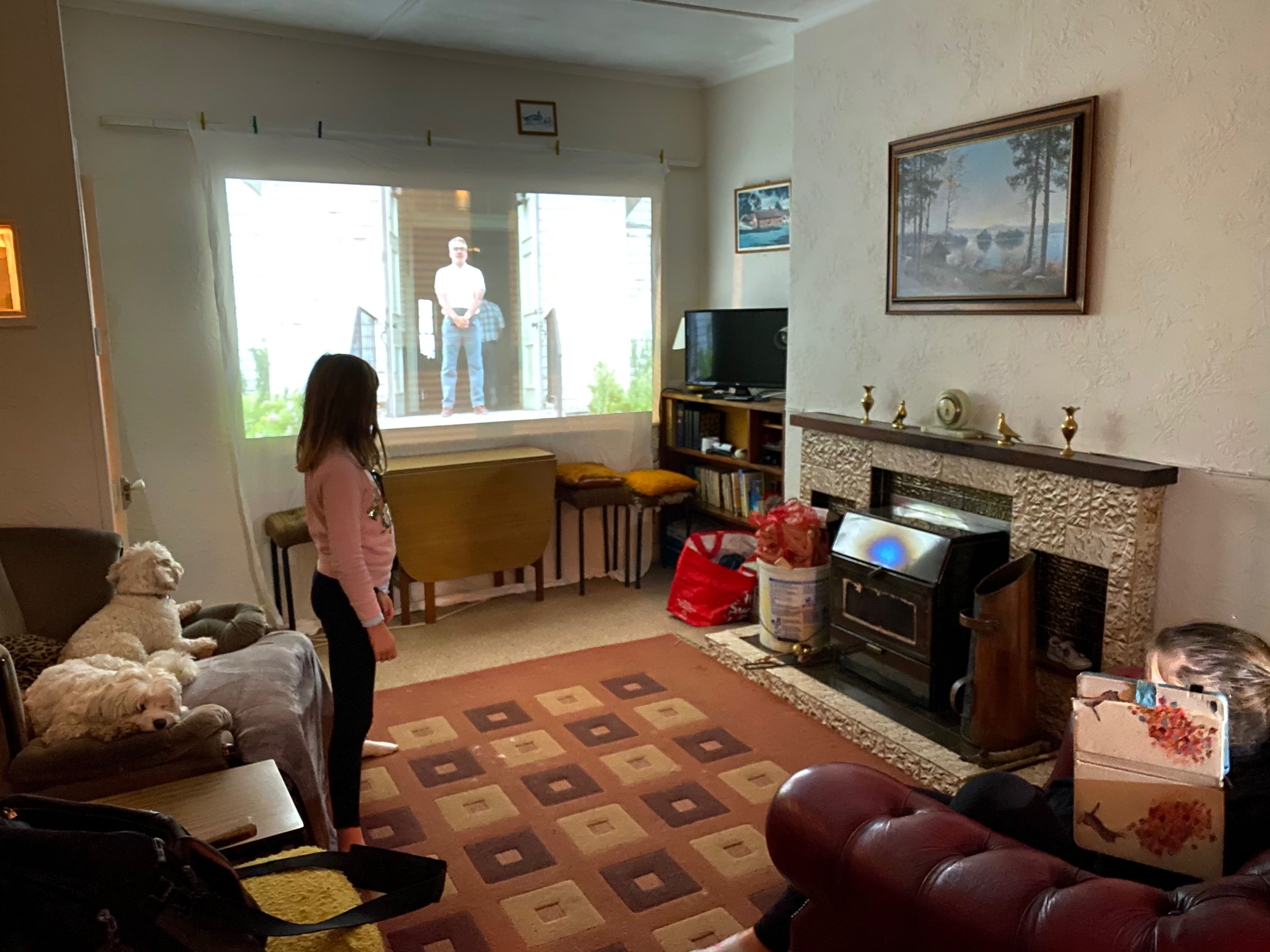 A film projected onto an old white sheet pegged across the sitting-room window, the dogs on the sofa — the cottage in family use before the work.