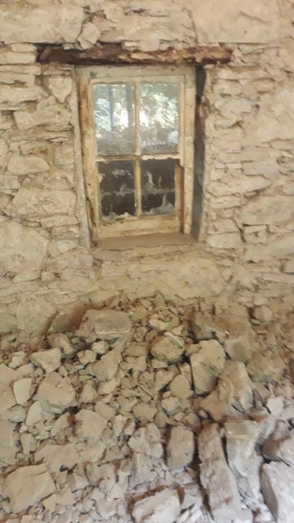 The plaster stripped from the kitchen wall to reveal the original rubble stone and a small deep-set window, sealed up and forgotten.