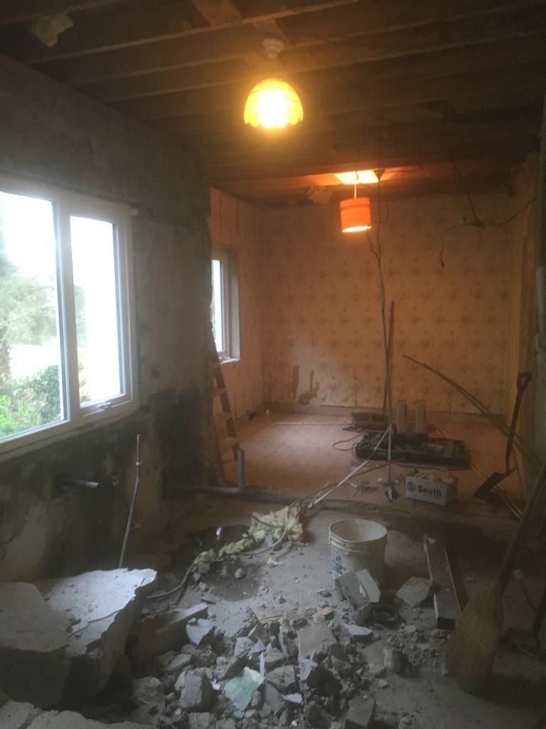 A room opened up after the dividing wall was taken out, the ceiling back to its joists and the floor broken open.