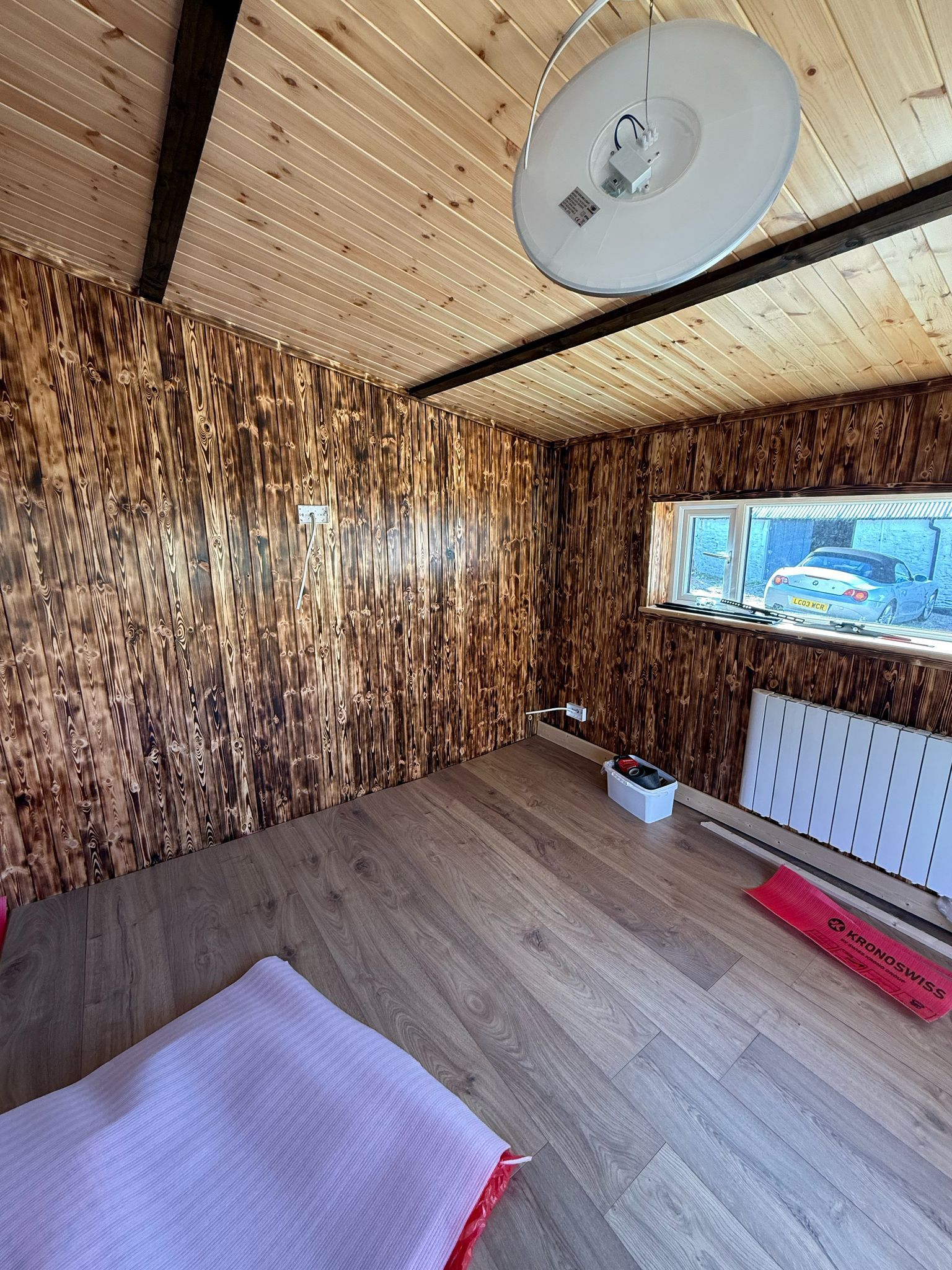 The finished games room — burnt-pine walls, a pale tongue-and-groove ceiling and a light oak floor.