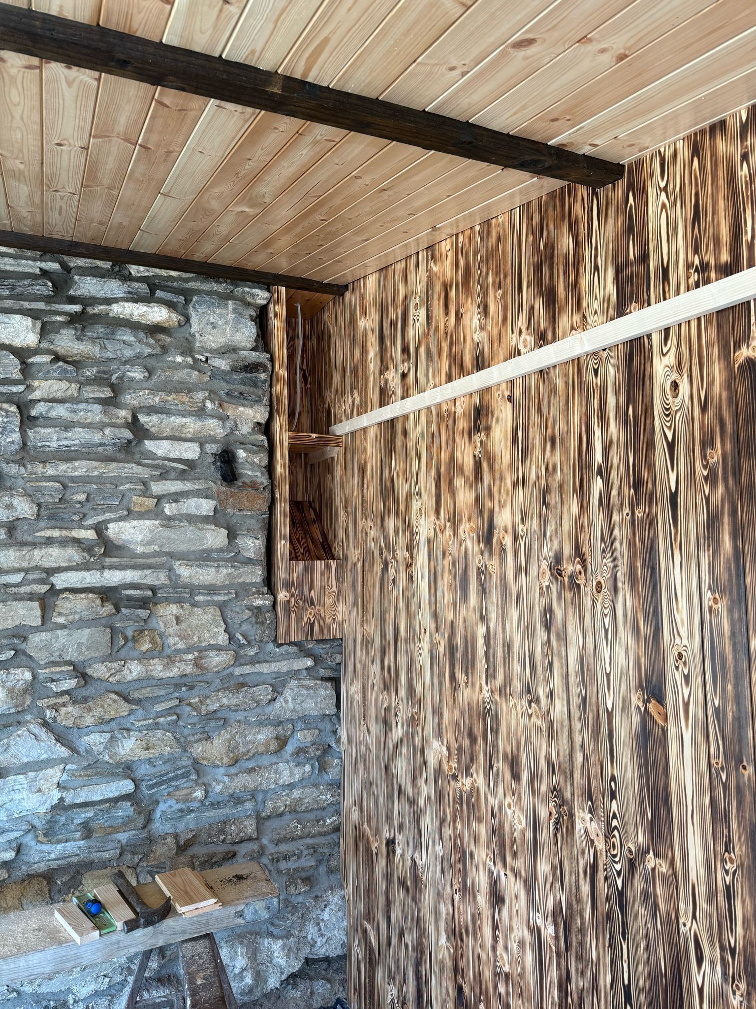 Close detail of the charred shou-sugi-ban pine cladding — distinctive black-and-amber burnt grain.