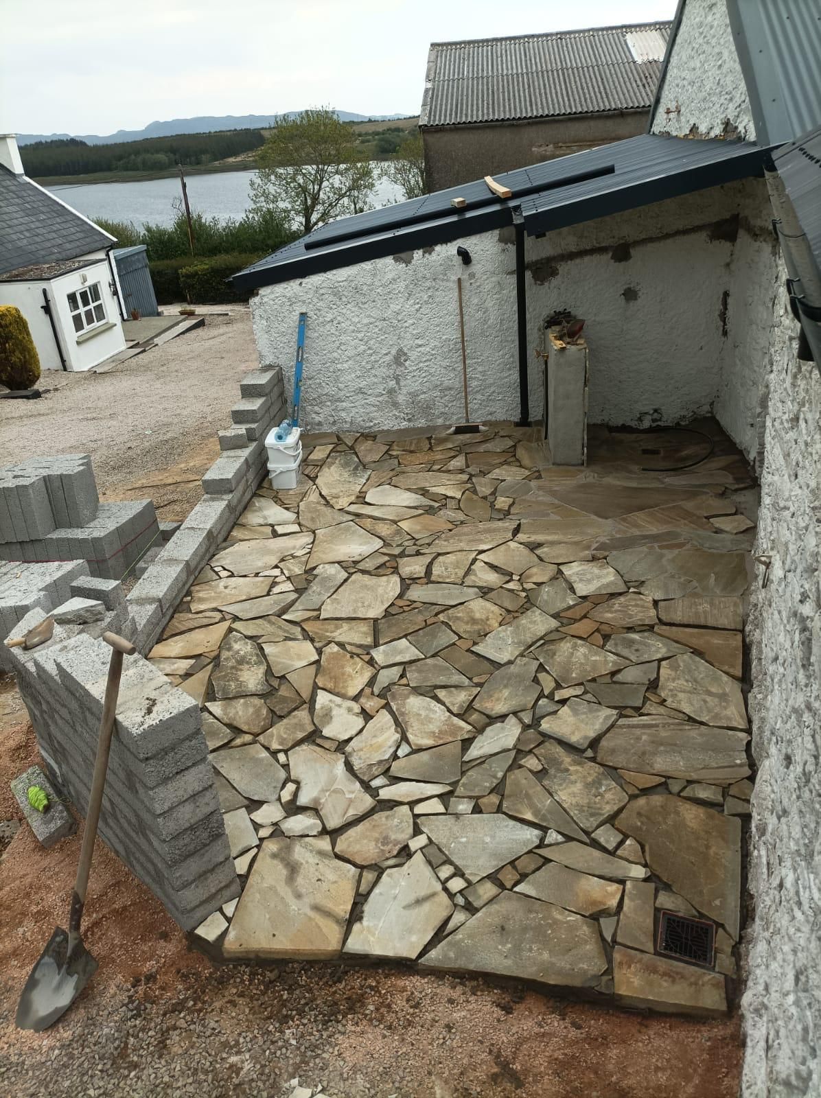 The first of the Donegal Quartz crazy-paving patio going down outside the sauna, Mulroy Bay glimpsed beyond.