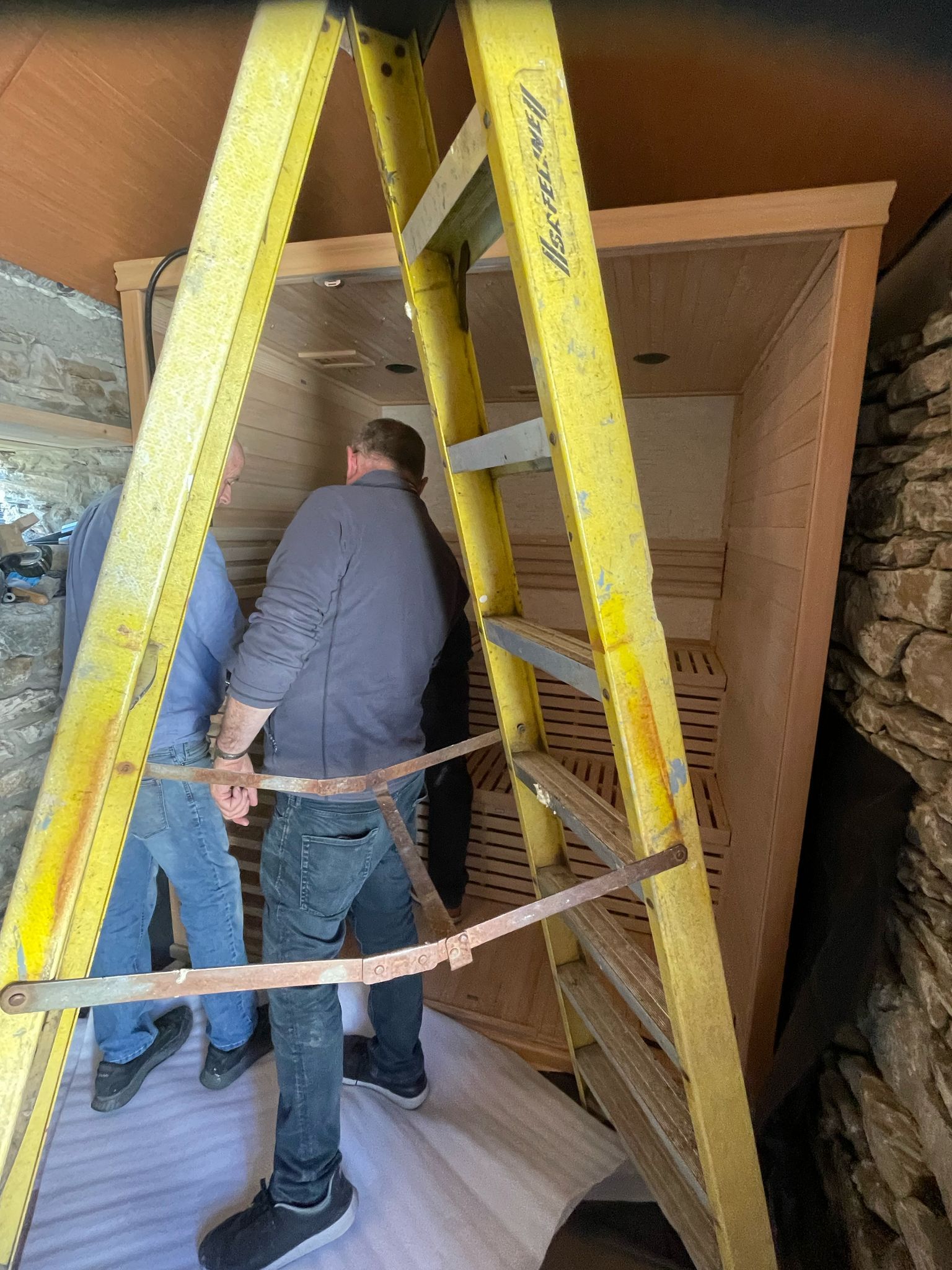 The sauna cabin being assembled on site inside the old stone shell, pine cladding going up.