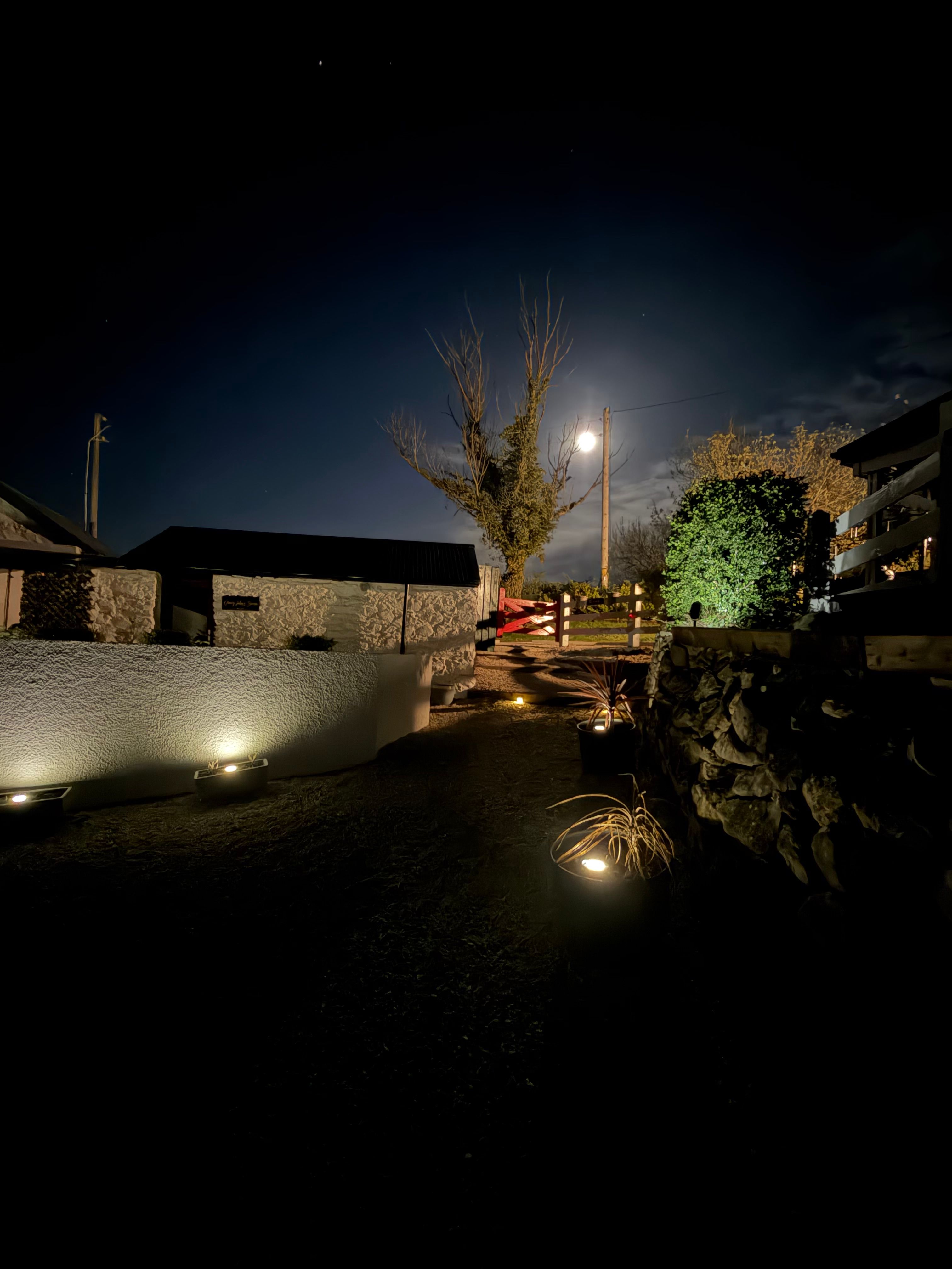 The sauna courtyard at night, dry-stone walls and planters caught in warm uplight