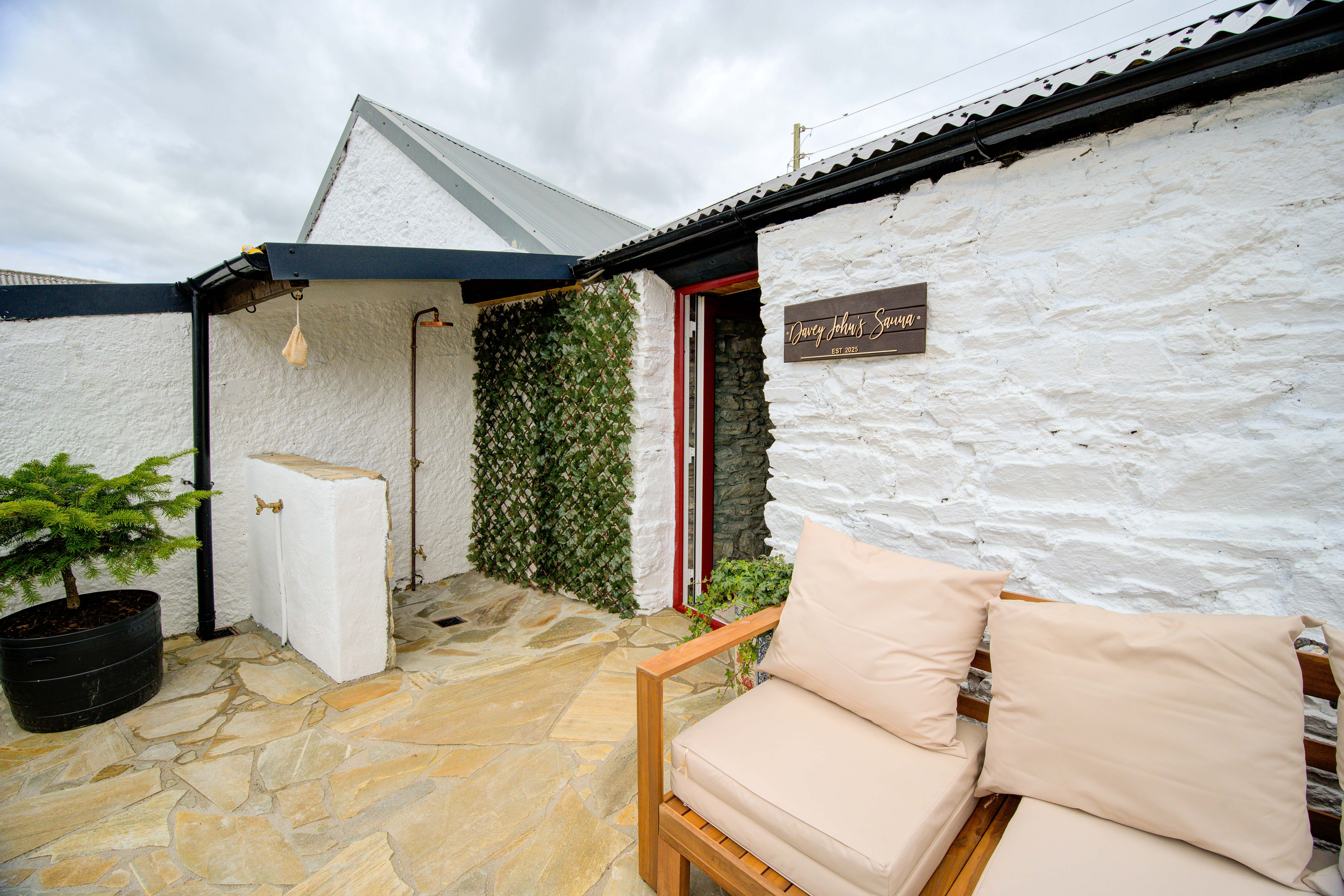 The sauna’s red-framed glass door and the copper shower from the patio