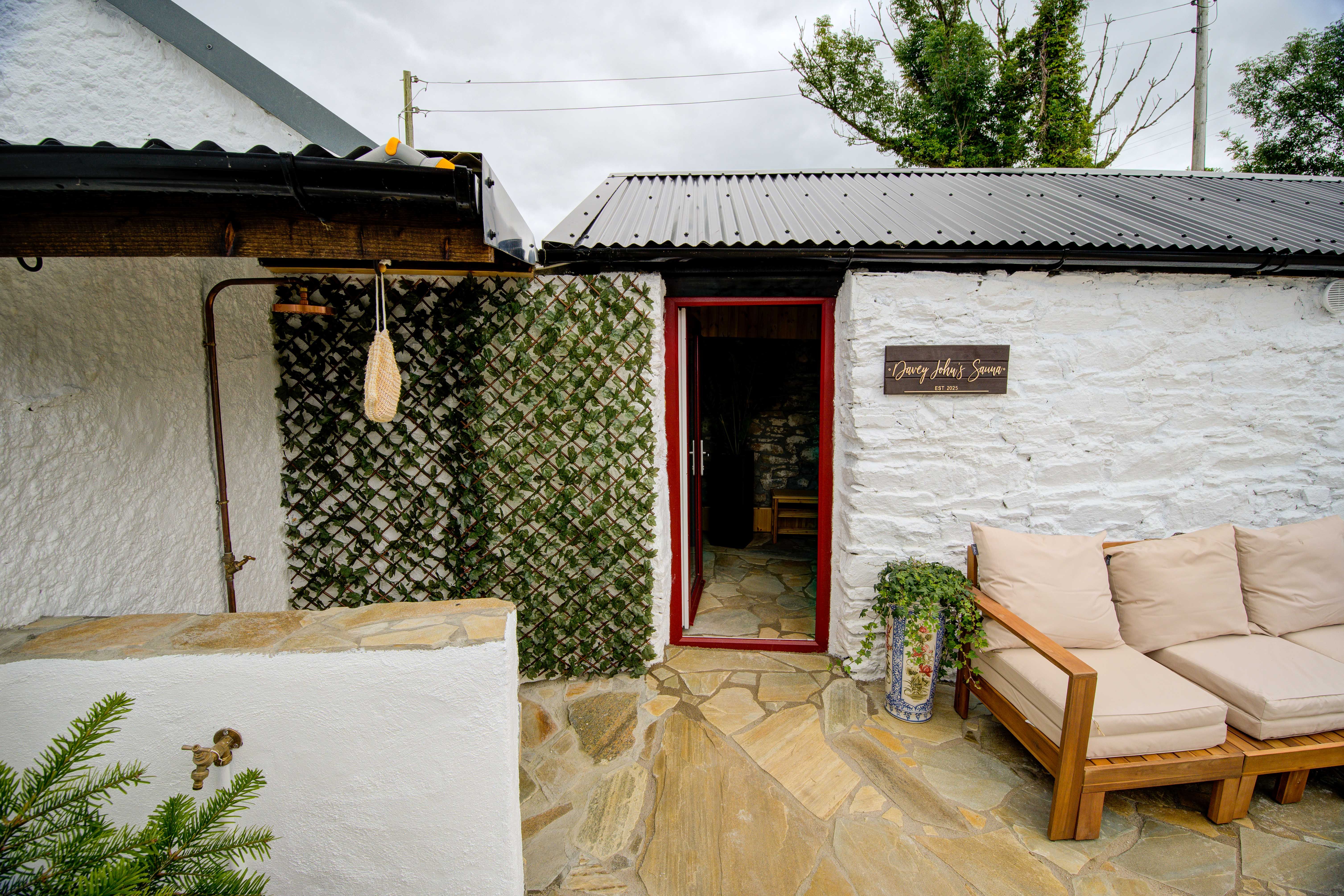 The sauna's red door open beside its sign, under an overcast sky