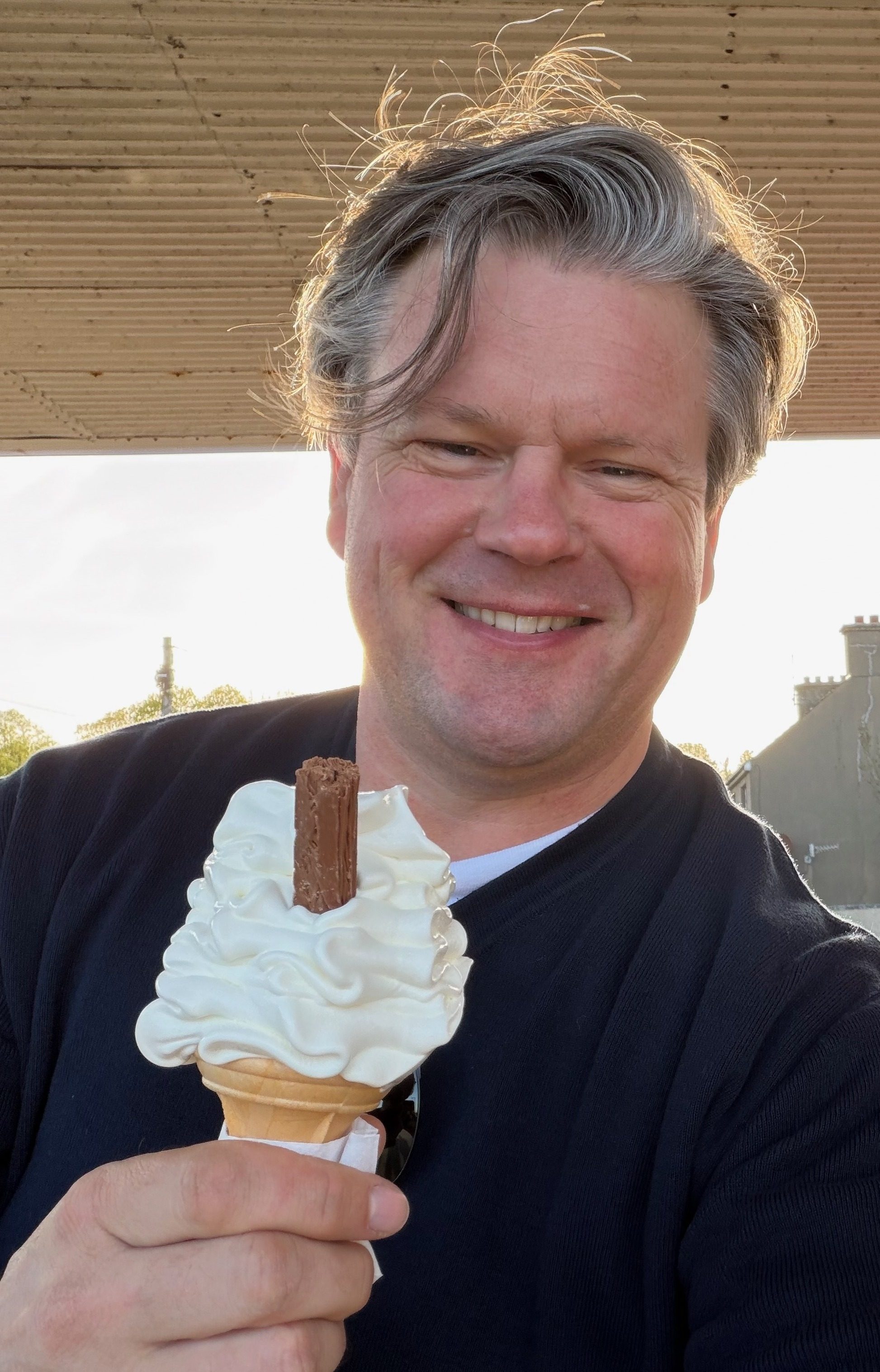 Shane Teskey, the host of Davey John’s Forge, smiling outdoors with a 99 ice cream.